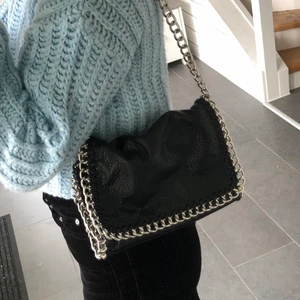 Väska - En svart väska med silvrig kedja. Kedjan går att ha på olika sätt man kan ha den andning kost under armen eller lång över axeln. Väskan är ifrån scorett.💜