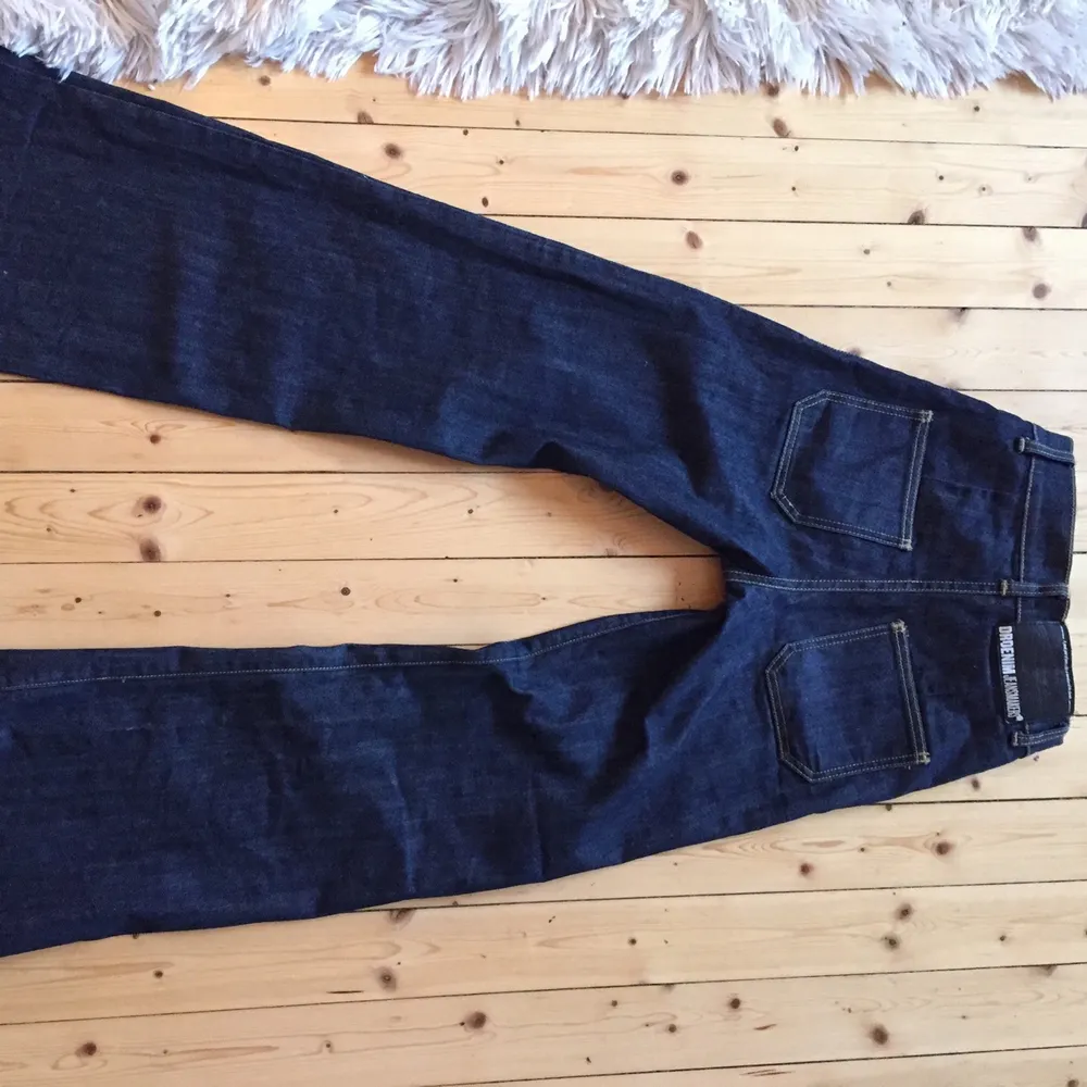 Ett par bootcut jeans i mörkblått jeanstyg från Dr. Denim Jeansmakers. Fickorna är mindre än vad standard jeansfickor är. Jeansen har även istället för dragkedja som gylf, knappar hela vägen upp. Har medelhög midja. Byxorna är knappt använda och ser ut som nya. Strl 28/32 men skulle själv säga att dem sitter som 27/32.. Jeans & Byxor.