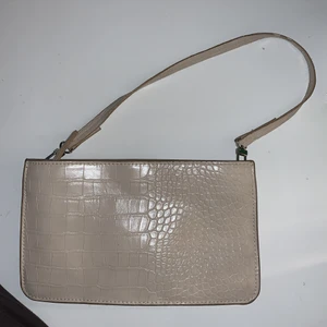 Beige handväska - Baguettväska i beige ormskinn. Två fack med dragkedja, i gott skick