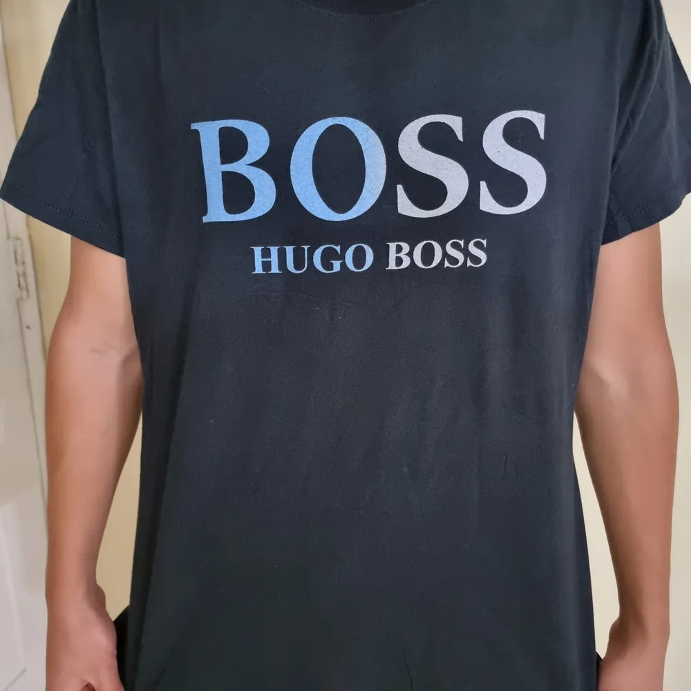Oanvänd Hugo Boss t-shirt med centrerad text och svartblå bakgrund. Simpel design fu kar med det mästa. Framhäver dina armar och är väldigt behaglig att ha på sig.       (!Tar häldst swish!). T-shirts.