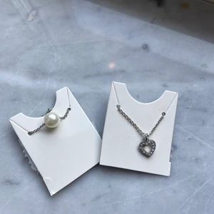 Silvriga halsband - Två silvriga fina halsband med varsin liten berlock. Oanvända och köpta på glitter💕köparen står för frakt!