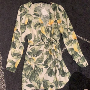 Jumpsuit - En söt och somrig jumpsuit med ett band som knyts runt midjan. Bandet gör att det istället ser ut som en klänningen. Helt oanvänd med prislappen kvar. Kostade 350 kronor. Storlek 38.