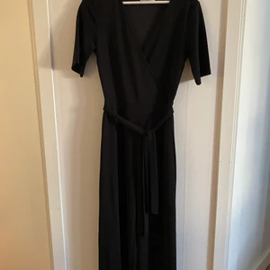 Svart byxdress - Säljer denna fina byxdress med omlottmodell och knytning i midjan då den aldrig kommit till användning, benländen är av kortare modell. Nypris 549kr säljer för 100kr💕