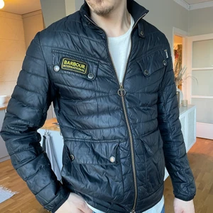 Barbour jacka blåsvart HERR - Herrjacka från Barbour International. Strl M. Kan inte avgöra om den är mörkt marinblå eller svart, något däremellan. Använt skick, slitningar på knappar, en söm på höger ärm som gått upp (inget som syns supermycket) och två hål på ryggen (det större av hålen på sista bilden). 