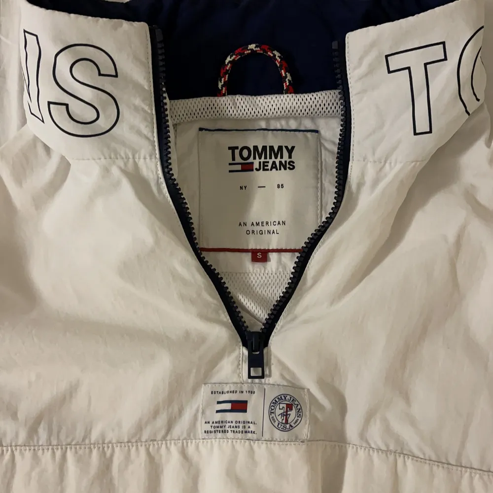 Säljer denna suuupersnygga unisex vindjackan från Tommy Hilfiger pga för liten. Använd väldigt lite, inga fläckar eller skador - bra skick. En jacka med många snygga detaljer som ex ett stort Tommy Hilfiger märke på vänstra armen. Det finns även en luva man kan ta ut som på bilderna ligger i kragen. Så man kan bestämma lite själv om man vill ha luva på jackan eller inte. Köpt för 1 600kr. Säljer för 400kr. Passar både för S och M💕. Jackor.