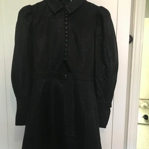 Adoore klänning (aldrig använd) - Adoore klänning. Från party collection. Aldrig använd, lapp sitter fortfarande kvar. Storlek M (liten i storleken dock). Jättefin svart klänning med puffärm, skimmer och en cutout under bysten. 