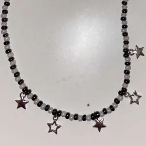 Halsband med stjärnor, vita och bruna pärlor. 