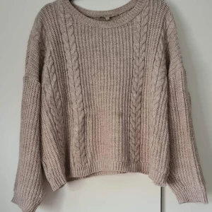 Stickad tröja i ullblandning - Oversize lite croppad stickad tröja. Översiksbilderna är lite orättvisa gällande färg, den närmare tagna bilden visar mer rättvist hur den ser ut i verkligheten. Använd men bra skick! (Beige/grå)