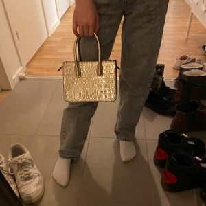 Liten guldig väska  - Säljer min guldiga väska från hm i bra skick, använd max 2 ggr. Pris 100kr + frakt.