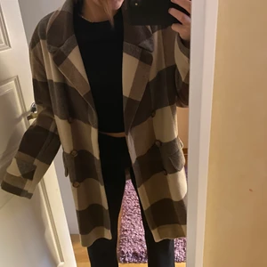 Kappa - Brun och vit-rutig kappa som knappt är använd. Den går ungefär till knäna på mig som är 168 och rak i modellen. Skriv vid frågor. Köpare står för frakt.