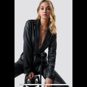 Leather blazer från NAKD - Skitsnygg blazer i fake-skinn med knytband från NAKD. Knappt använd och i nyskick. Storlek 34 men passar även 36. Kollektionen Anna Nooshin x NAKD.