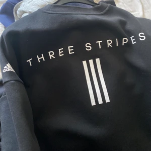 Sweatshirt svart adidas - Cool sweatshirt i en lite längre modell från adidas med snyggt tryck på ryggen. Den är bara svart från framsidan med ett adidasmärke på armen. På ryggen står det three stripes. Storlek är Xs men skulle säga att den är xs-s. Kan skicka fler bilder😇