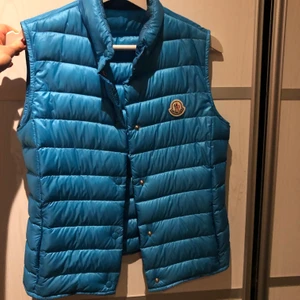 Moncler väst strl 0/xs - Jättefin Moncler väst i en unik ljusblå/ turkos färg. Västen är i jättefint skick. Den har knappar istället för dragkedja och två stycken framfickor. Perfekt att ha på hösten/ våren eller under en jacka på vintern.  Varan skickas när pengarna sitter på kontot!