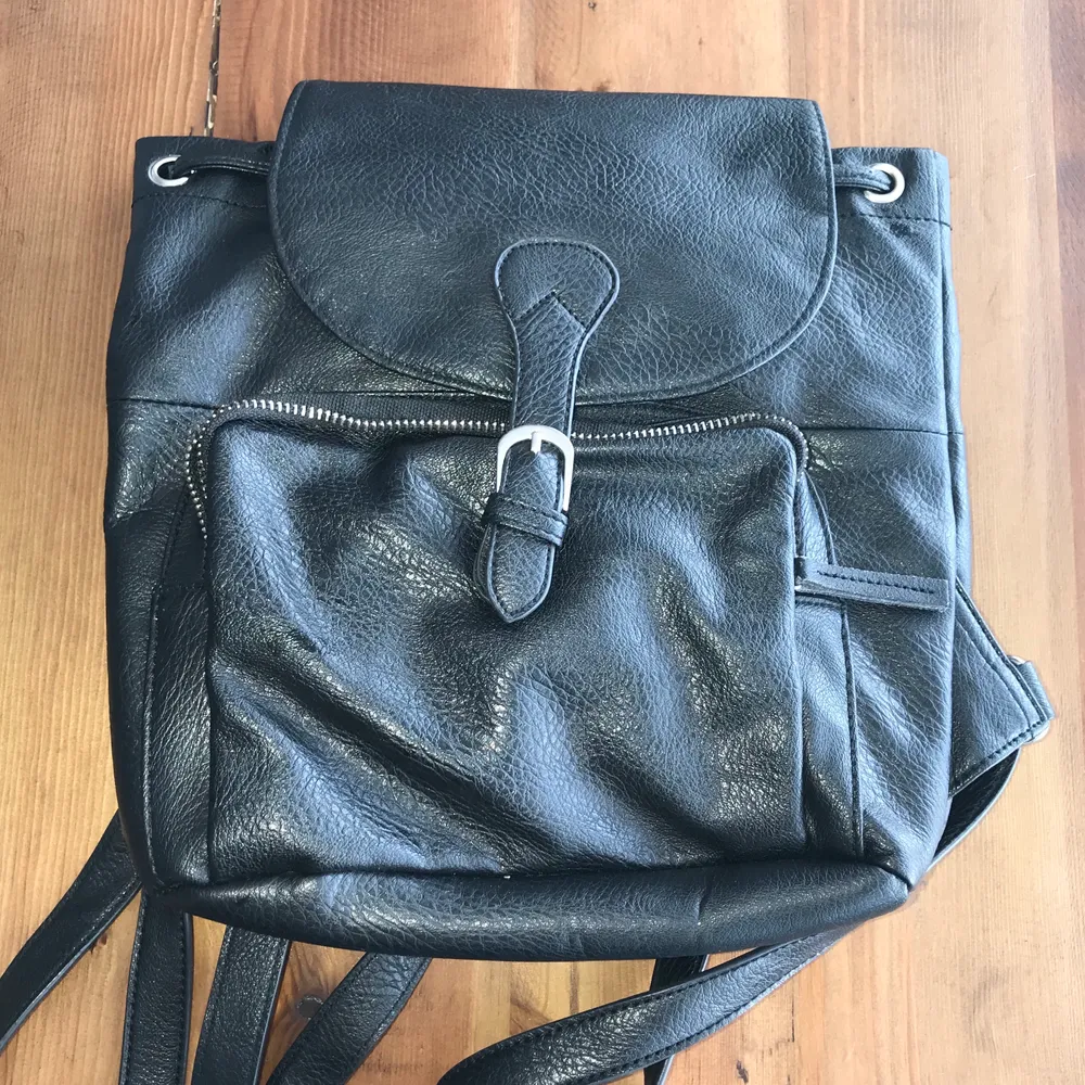 Black vegan leather drawstring closure backpack. Can fit an iPad Pro (10”)  or Air. Great used condition. Magnetic clasp. No fading, loose stitching, holes, tears, rips, snags. Lining is great. Please note the inside of the flap. Smoke and pet free storage space. No other flaws to note.  Happy to bundle. Will gladly take more pics. Disclaimer: Please expect some general wear in all secondhand pre-loved items as they have lived a previous life, so don't expect a mint item. . Väskor.