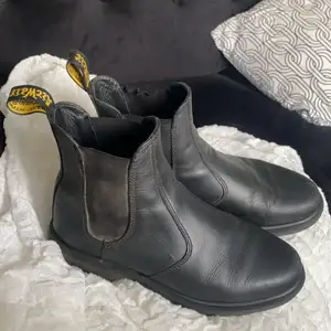 Dr. Martens (Laura Black). Svarta Chelsea-boots i läder med elastiska sidor. Luftfjädrande gummisulor. Goodyear-welted produkt. Bra grepp och halkmotstånd. Köptes förra hösten för 1900 kr. Storlek 41. Använda men i gott skick (se bilder).