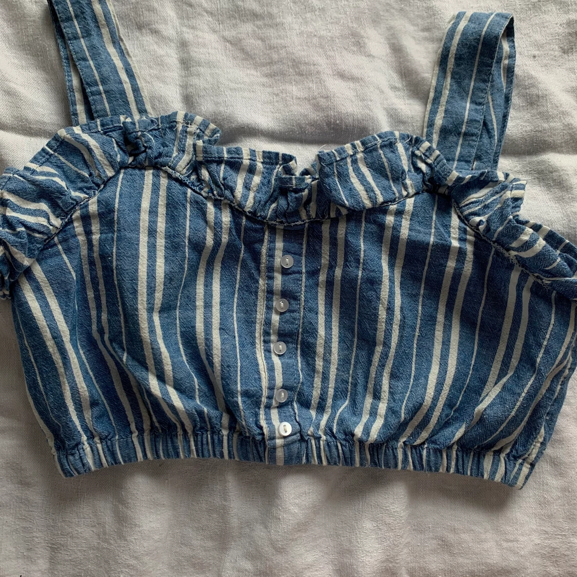 Blå och vit randig topp med knappar.