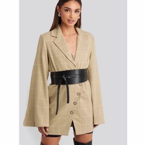 NA-KD kavajklänning/blazer - (Första bilden är lånad) Riktigt snygg kavajklänning från NA-KD som aldrig kommit till användning, köptes för 699:-. Lite oversized passform i ärmarna och tight i midjan. Har även det svarta skärpet till midjan om det önskas! Jag är 173cm lång. Köparen står för frakten.
