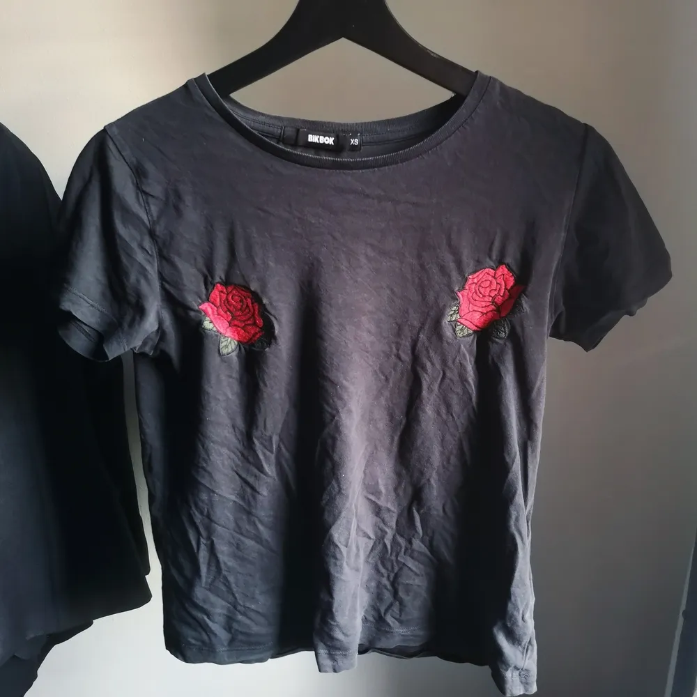Säljer denna svarta T-shirten från Bikbok med röda rosor på framsidan, storlek XS❤️. T-shirts.