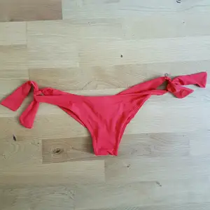 Snygg, röd, brasilian bikiniunderdel med knytning på båda sidorna, passar stl: XS-S. Stil halvstring.