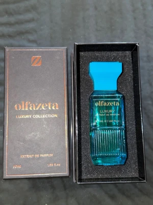 Sole di positano T ford: Olfazeta Luxury Collection parfym - Sole di positano tom ford: Lyxig parfym från Olfazeta Luxury Collection i en elegant turkos glasflaska med räfflad design och matchande blått lock. Flaskan rymmer 50 ml extrait de parfum och levereras i en svart presentask med gulddetaljer. Perfekt för dig som gillar exklusiva dofter.