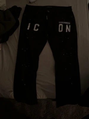 Svarta Dsquared2 ICON jeans och ljusblåa Dsquared2 jeans - Svarta jeans från Dsquared2 med stor vit 'ICON'-text framtill och Dsquared2-logga på bakfickan. Jeansen har klassisk femficksdesign och är tillverkade i ett stretchigt bomullsmaterial. Snygg och modern look med raka ben. Och ett par ljusblåa Dsquared2 jeans med lite slitage stil på framsidan, äkta, priset är inte ristat i sten pris kan gå ner vid snabb affär, priset är för båda jeansen.
