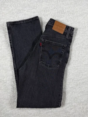 Levi’s Premium Ribcage Straight Jeans – Grå/Svart – W24 – High Waist - Stilrena Levi’s Premium Ribcage Straight jeans i tvättad grå/svart denim. En populär modell med hög midja och raka ben – perfekt för både vardag och mer uppklädda outfits.  Detaljer: 	•	Märke: Levi’s Premium 	•	Modell: Ribcage Straight 	•	Färg: Grå / washed black 	•	Midja: High waist 	•	Ben: Straight leg 	•	Stängning: Knappgylf 	•	Original Levi’s-detaljer och nitar  Storlek: 	•	Märkt storlek: W24 	•	Midja (platt): ca 32 cm 	•	Ytterlängd: ca 101 cm 	•	Innerbenslängd: ca 67,5 cm