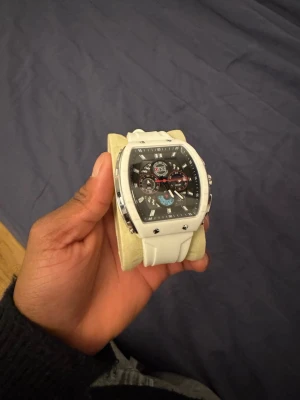 Vit sportig klocka från ONS - Snygg och modern klocka från ONS med vit rem och svart urtavla. Klockan har flera små urtavlor, silverfärgade detaljer och en robust design. Perfekt accessoar för dig som gillar en sportig och stilren look.