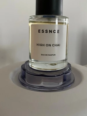 ESSNCE High On Chai Eau de Parfum - Parfymflaska från ESSNCE med doften High On Chai. Flaskan är cylindrisk i genomskinligt glas med svart rund kork och enkel vit etikett med svart text. Innehållet är ljusgult och ger ett stilrent och modernt intryck. Perfekt för dig som gillar unika och kryddiga dofter. Fantastiskt doft, bara använd några gånger 