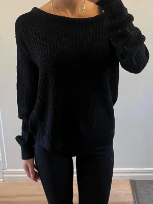 Svart stickad tröja med rund hals - En svart stickad tröja med avslappnad passform och rund halsringning. Tröjan har långa ärmar och är ribbstickad för en mysig känsla. Perfekt för lager-på-lager och enkel att matcha med olika outfits.