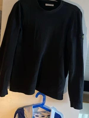 Svart sweatshirt från Stone Island - Säljer denna svarta  sweatshirt från Stone Island storlek S med klassisk rund hals och ikonisk patch med logga på vänster ärm. Tröjan har långa ärmar och är gjord i mjukt bomullsmaterial. Perfekt för en clean och stilren look. Swearahirten är köpt på NK i Göteborg för några år sedan och har hållit sig i ett mycket gott skick bara höra av er vid frågor, ha de gött!! 