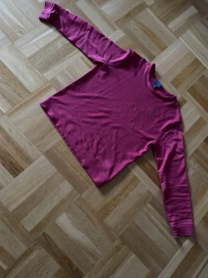 Mörkröd tröja från Polo Ralph Lauren - Säljer en mörkrosa långärmad tröja från Polo Ralph Lauren. Tröjan har rund halsringning och en liten broderad logga på bröstet. Tillverkad i mjukt bomullsmaterial som är skönt mot huden. Perfekt för dig som gillar klassisk och enkel stil. Använd endast ett fåtal gånger då jag tycker den är för stor för mig