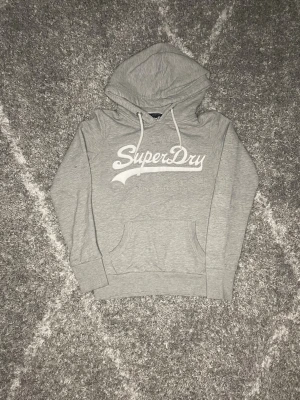 Superdry hoodie grå - En grå fin Superdry hoodie i Mycket bra skick, den är i storlek S, passar perfekt nu till vintern det är bara att skriva vid frågor. :) ☃️❄️