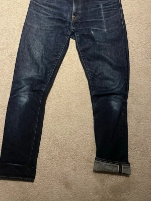 Selvedge Japan Blue Jeans ”Circle” - Säljer ett par mörkblå jeans med raka ben och klassisk femficksmodell. Jeansen har snygga slitningar och uppvikta benslut för en avslappnad look. Tillverkade i kraftig denim som ger en tidlös känsla. Perfekta till sneakers eller boots.