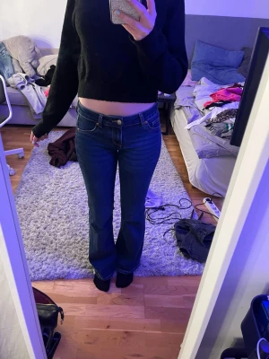 Mörkblå bootcut jeans med låg midja - Säljer ett par mörkblå bootcut jeans med låg midja och klassiska fickor både fram och bak. Jeansen har en snygg passform som sitter tajt över låren och släpper ut vid vaden. Perfekta för dig som gillar lågmidjade jeans och vill ha ett par supersnygga byxor!