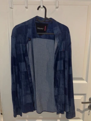 Patchwork jeansjacka från Dsquared2 - Snygg jeansjacka från Dsquared2 i patchwork-mönster med olika blå nyanser. Klassisk krage, knäppning framtill och avslappnad passform. Perfekt för dig som vill sticka ut med en unik denimlook.