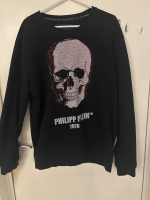 Svart Philipp Plein sweatshirt XXL - Cool svart sweatshirt från Philipp Plein med tryck framtill och texten 'PHILIPP PLEIN 1978'. Tröjan har rund halsringning och ribbade muddar vid ärmslut och nederkant. Perfekt för en streetwear-look.