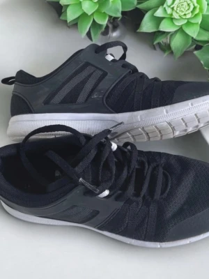 Svarta damsneakers med vit sula, SOC, storlek 38,  - Snygga svarta sneakers med ovandel i mesh och detaljer i syntet. Skorna har vita sulor och svarta skosnören. Perfekta för en sportig och avslappnad stil. Lätta och bekväma med modern design. 