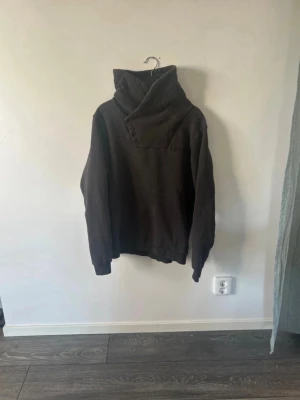 Svart/grå  G-star RAW - Säljer en svartgrå tröja med unika knappdetaljer. Tröjan har långa ärmar, ribbade muddar och en oversized passform. Perfekt för dig som gillar streetwear och vill ha något som sticker ut. Materialet känns mjukt och bekvämt, troligen bomullsblandning.