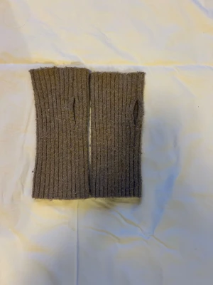 Beige stickade handledsvärmare - Säljer ett par ribbstickade handledsvärmare i beige. De är fingerlösa och har tumhål, perfekta för dig som vill hålla händerna varma men ändå kunna använda mobilen. Passar till både höst och vinter.