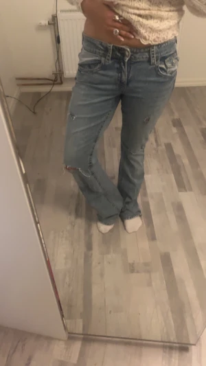 Blå bootcut jeans med slitningar - Köptes för 400kr Säljer ett par ljusblå bootcut jeans med slitna detaljer då dom e för långa för mig som e 162. Passar någon som e runt 170. Jeansen har klassisk femficksmodell, låg midja och är tillverkade i jeansmaterial. Perfekta för dig som gillar en avslappnad och trendig look.