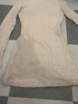 Beige ribbad tröja - Säljer en beige ribbad tröja med lång ärm. Tröjan  har en kroppsnära passform och är tillverkad i ett mjukt stickat material. Perfekt för dig som gillar enkel och stilren design med lite struktur i tyget.