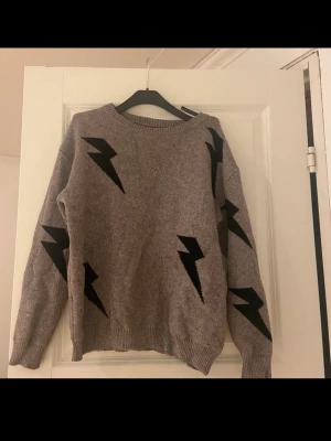 Grå stickad tröja med blixtar - Säljer en grå stickad tröja då den är för liten för mig, stl S men skulle mer säga XS
