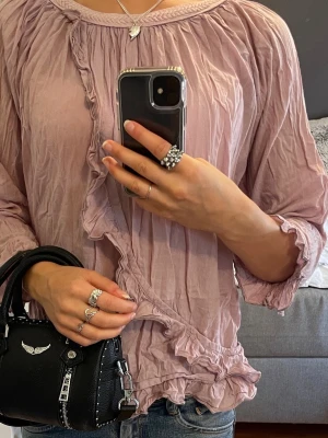 Rosa volangblus - Supersöt ljusrosa blus från Havana med volangdetaljer längs nederkant och ärmslut. Trekvartsärmad och lös passform och flätad kant upptill. Passar XS/S