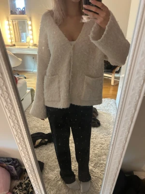 Beige fluffig kofta med fickor - Mysig och fluffig beige kofta med v-ringad hals och två stora fickor framtill. 