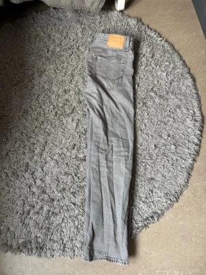 Grå jeans från Jack & Jones - Snygga grå jeans från Jack & Jones med klassisk rak passform. Jeansen har en ljusgrå tvätt och detaljer som knappgylf och läderpatch bak i midjan. Perfekt för dig som gillar en enkel och stilren look.