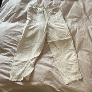 Beiga linnebyxor från H&M med snörning - Ett par beiga linnebyxor från H&M i storlek XS. De har elastisk midja med snörning och raka ben. Materialet är en linneblandning som känns luftigt och perfekt för varmare dagar. Ej genomskinlig. Innerbenslängden är 65 cm.