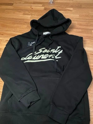 Säljer min Yves Saint Laurent hoodie - Säljer min yves saint laurent hoodie! Den e svart med en vit logga. Aldrig använd helt nyköpt och jätte bra skick! Den är storlek M men sitter rent för litet för en M den sitter som en S precis skulle kag säga! Köpt för 1400 så måste ha 1200 för den!☺️
