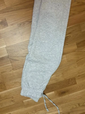 Grå mjukisbyxor från 157, storlek S - Säljer ett par ljusgrå mjukisbyxor från 157 i storlek S. Byxorna har resår och snörning i midjan, samt muddar vid bensluten. De är tillverkade i mjukt bomullsmaterial och har praktiska sidofickor. Perfekta för chill eller träning.