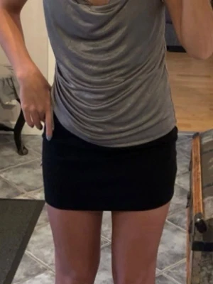 Grå omlott linnetopp från Zara - Säljer en snygg grå omlott linnetopp från Zara i storlek M (skulle dock säga att det är i storlek XS/S). Toppen har tunna axelband, draperad halsringning och en cool snörningsdetalj på sidan. Materialet är mjukt och har en lätt glansig finish som ger en lyxig känsla. Perfekt att styla med kjol eller jeans!