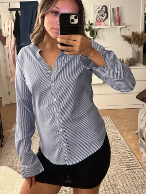 Blåvit randig skjorta med knappar - Säljer en klassisk blåvit randig skjorta med långa ärmar och knappar hela vägen framtill. Köpt på en saconhand